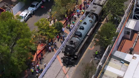 aerial view of a historic steam train in a city street with a crowd of people