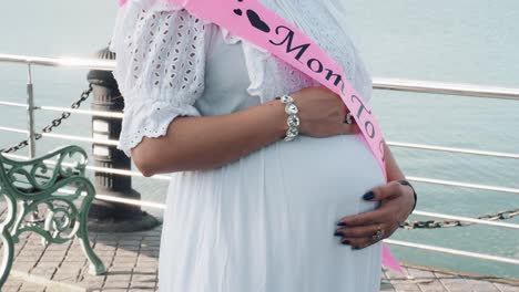 Indian-pregnant-woman-holding-her-belly-when-standing-near-the-lake