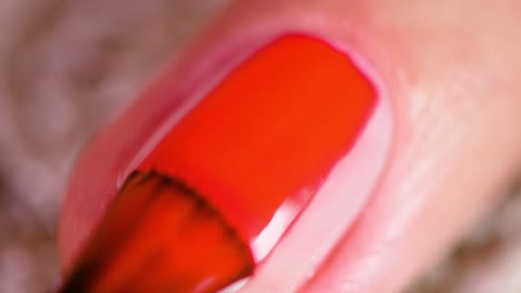 Bright-red-nail-polish-applied-on-a-fingernail,-macro-shot