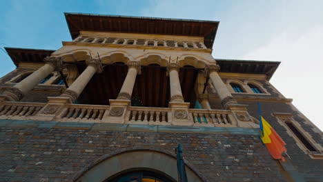 View of the mansion exterior with columns. Low angle view on the building fasade with Romanian flag.