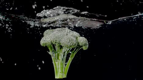 ramo colorato di broccoli che viene fatto cadere in acqua al rallentatore