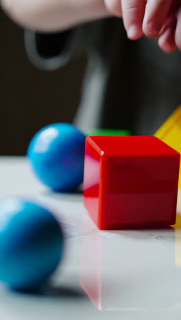 child playing with colorful geometric building blocks