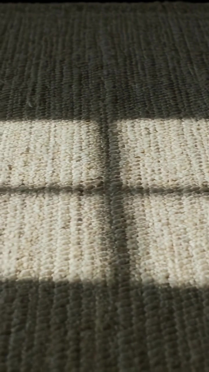 Video verticale: L'angolo del sole che cambia proietta una chiazza di luce in movimento e ombre a griglia su un tappeto intrecciato nella stanza