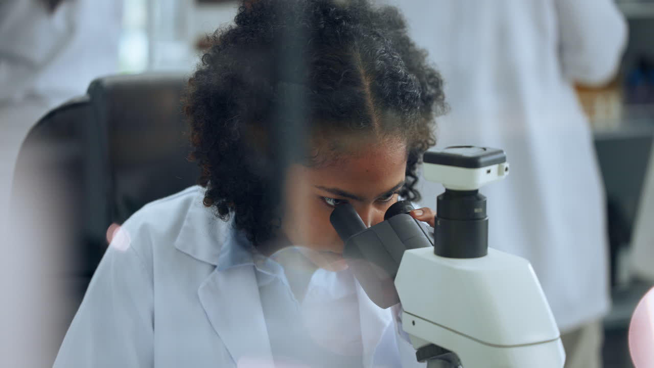 Giovane scienziata concentrata che usa il microscopio in laboratorio