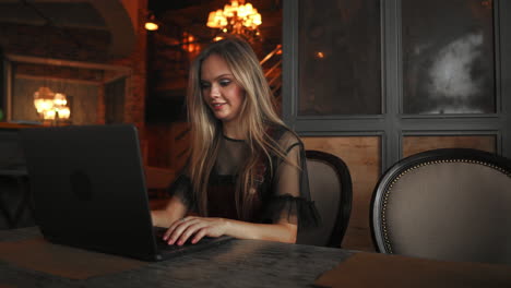 Happy-young-woman-drinking-coffee-and-using-tablet-computer-in-cafe