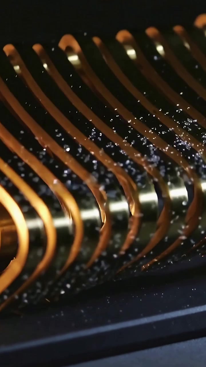 Video verticale: Telecamera che si inclina causando il rilascio di polvere da una bobina alettata su una base scura, avvolgimento in rame.