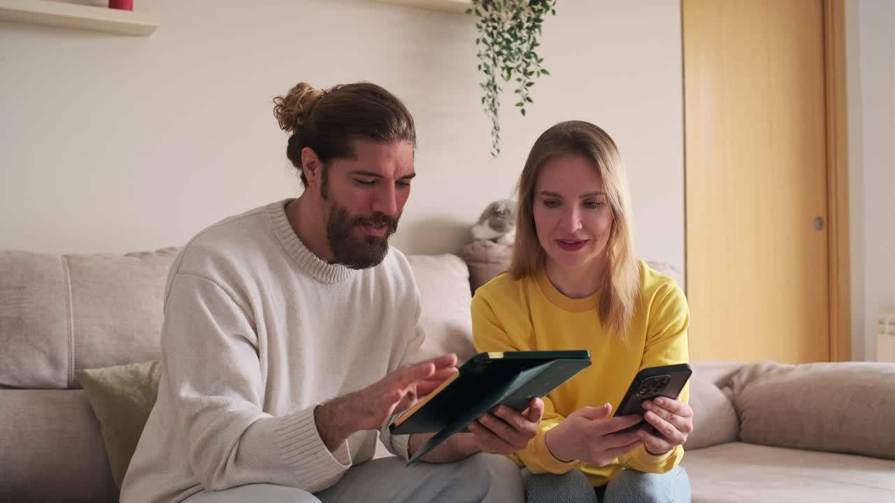 Couple using a tablet and smartphone at home