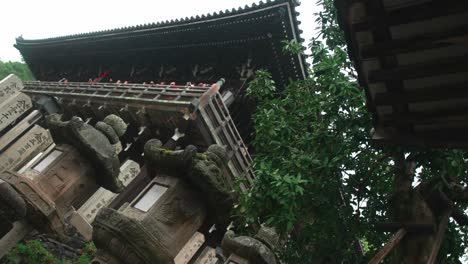 People-visiting-Buddhist-japanese-temple-in-Nara,-rainy-day,-4k