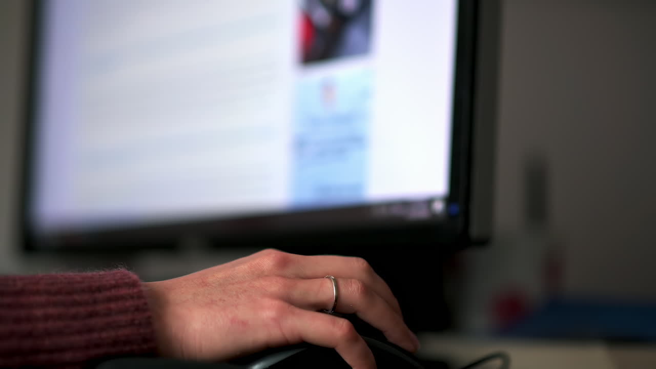 A person is focused on their work at a computer, typing with one hand. The screen displays text, while a warm atmosphere fills the room. Time appears to be afternoon