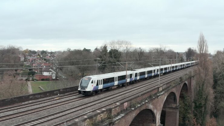 Dolly back profile drone shot of TfL rail train over Wharncliffe viaduct