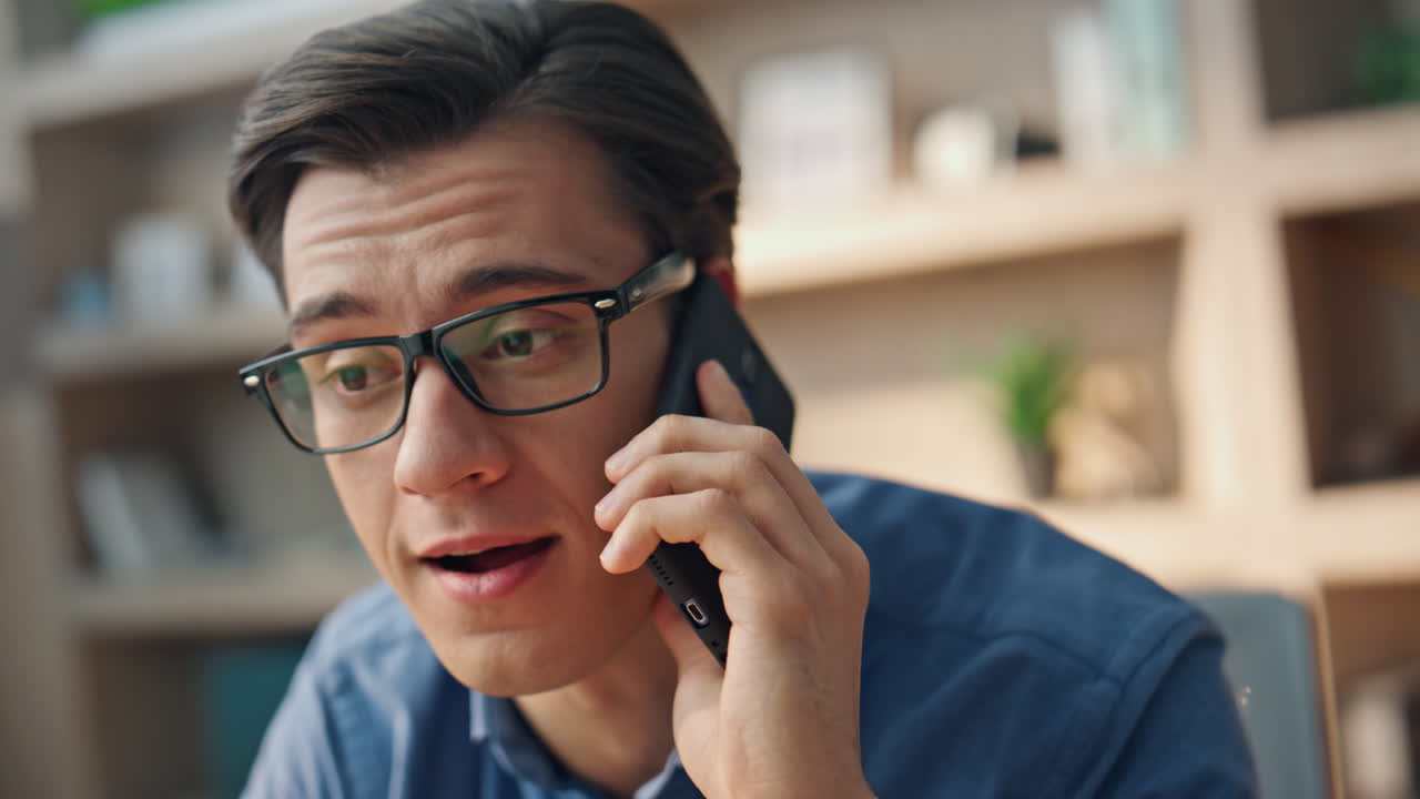 안경 남자가 드폰으로 사무실을 가까이에서 이야기하고, 프리랜서가 전화를 즐기고 있다.