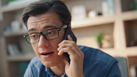 hombre con gafas hablando por teléfono móvil oficina de primer plano. freelancer disfrutando de una llamada telefónica