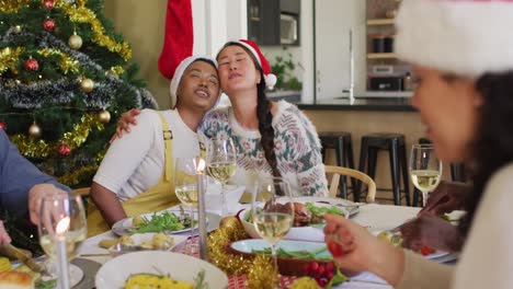 Two-diverse-female-friends-celebrating-meal-with-friends-at-christmas-time