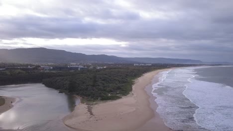 Fliegen-über-Eine-Wunderschöne-Insel-über-Einen-Flachen-Bach-Oder-Fluss-Und-Sandstrand-Mit-Welle-Bei-Sonnenuntergang