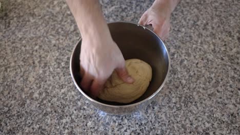 placing a sourdough ball into a metal mixing bowl with some oil, the dough is turned in the oil before setting aside to rise before forming into sourdough bagels and cooking