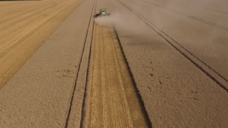 harvest drone pullback behind combine harvester in field, crop dust