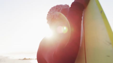 senior african american man holding surfboard on sunny beach