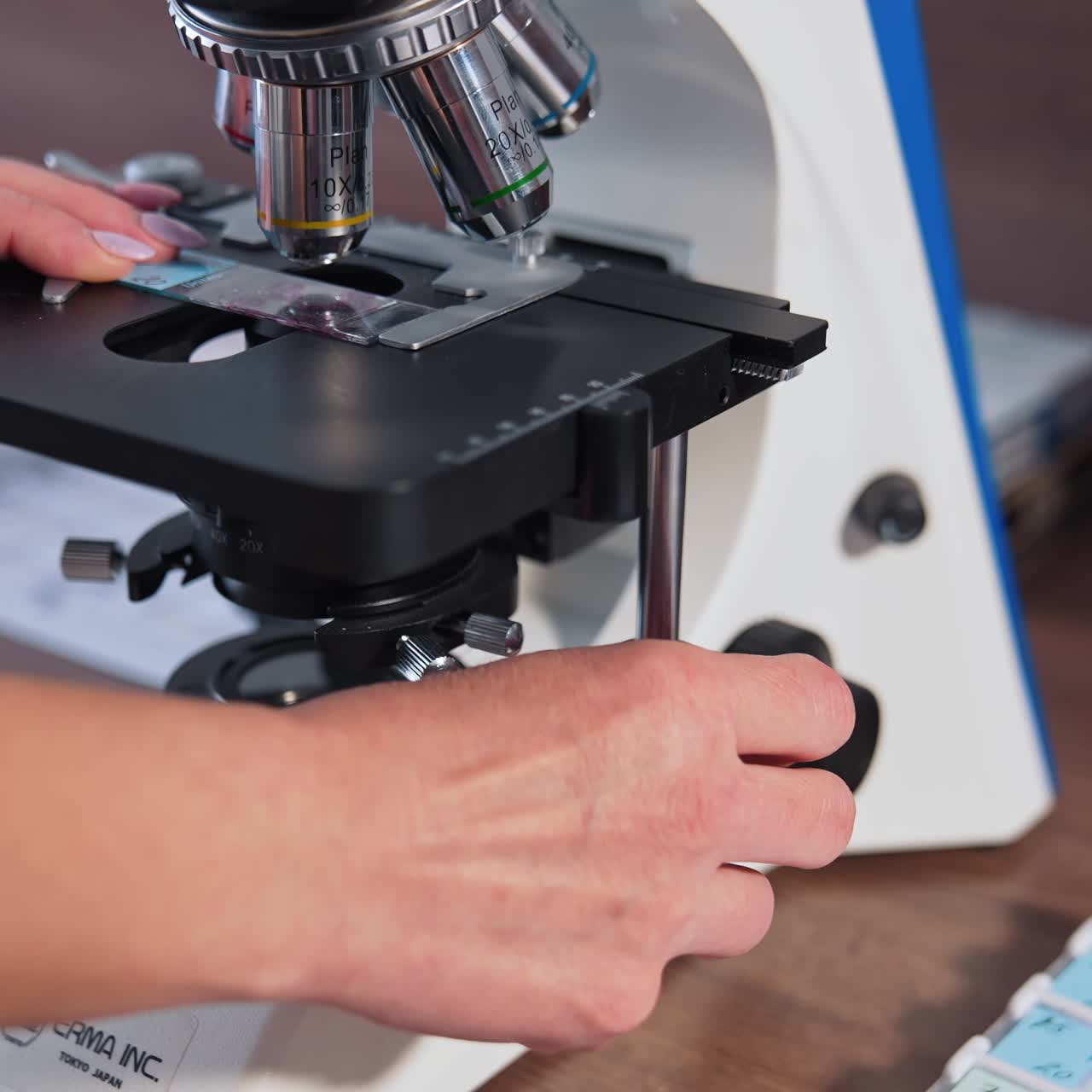 Scientific laboratory microscope examining drop. Close up shot of sample slide and microscope with metal lens at laboratory