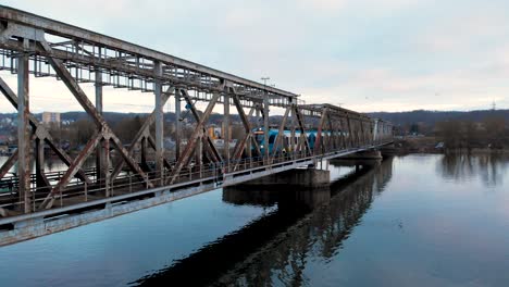 local train traveling at railway bridge over calm river near szczecin, poland