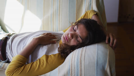 Relaxed-mixed-race-woman-lying-asleep-on-sofa-in-sunny-living-room