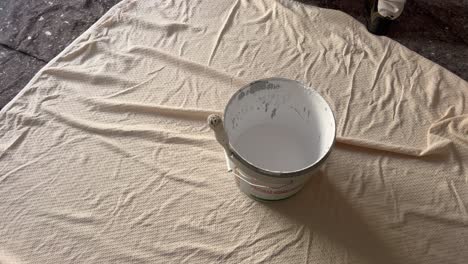 persona está usando rollo de pintura de color blanco, inundado en cesta de metal, comerciante responsable de la pintura y decoración de edificios