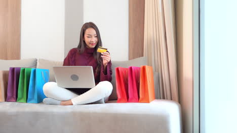 woman on couch holding credit card for online shopping payment slomo