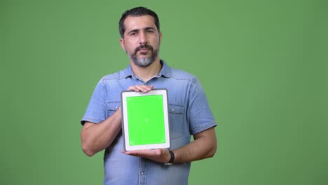 handsome persian bearded man showing digital tablet