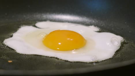 side view close up of egg gently cooking in medium temperature oil. protein rich breakfast healthy food