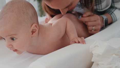 mother changing baby diaper at home infant lying on table mom cleaning toddler putting on new nappy caring for newborn 4k