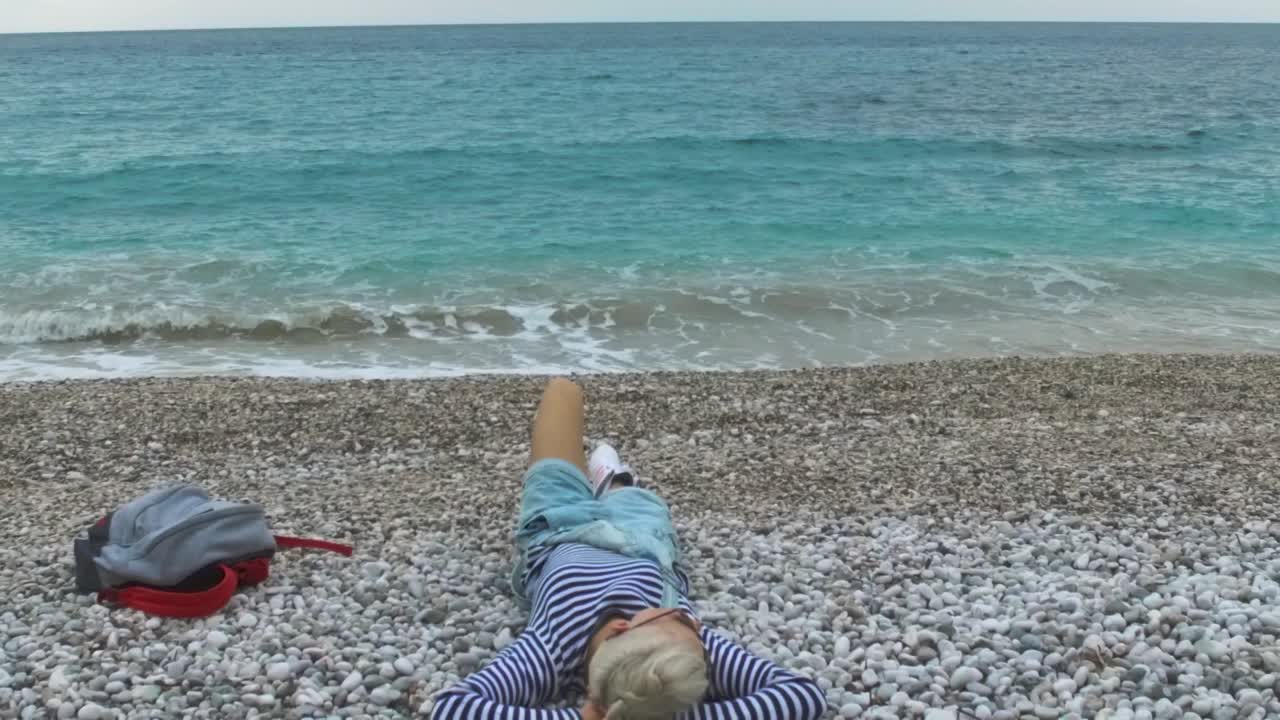 바다 의 자갈 해변에서 휴식을 취하는 여자