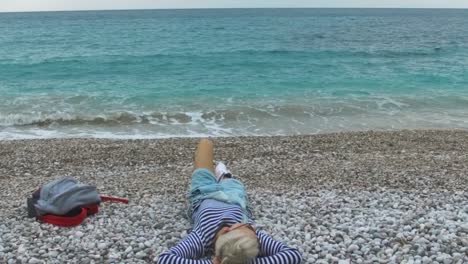 mujer relajándose en una playa de guijarros junto al océano