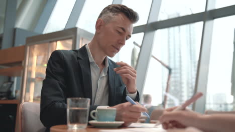 a business man look at some papers and takes some notes in a coffee shop