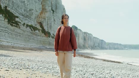mujer caminando por una playa por acantilados