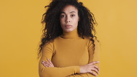 una mujer afroamericana segura de sí misma sobre un fondo naranja.