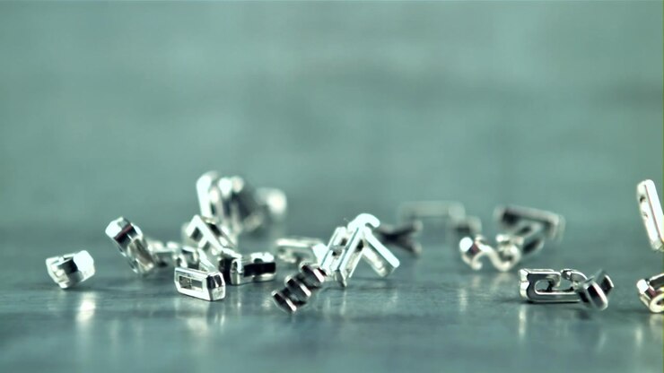 Slow Motion Close-Up of Silver Metal Letters Falling