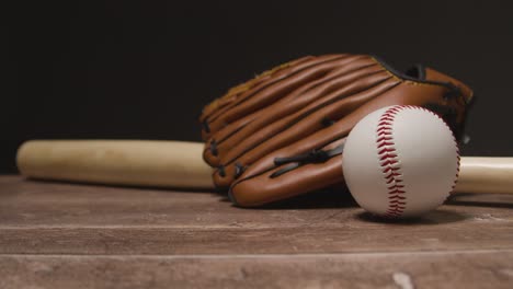 close up studio baseball still life with wooden bat and ball in catchers mitt on wooden floor 3