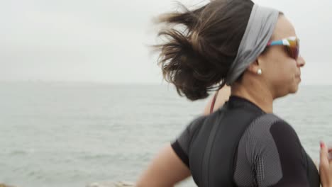 side view of focused female triathlete running along promenade