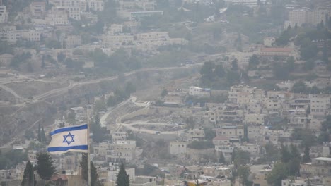 la bandera israelí ondeando al viento en jerusalén, israel, a las afueras de la ciudad vieja