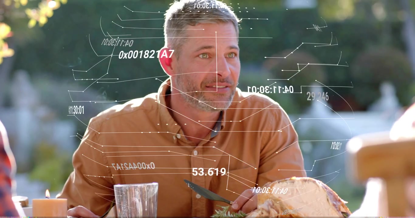 Middle-aged man raising knife carving turkey on family patio, technology readouts tracking motion