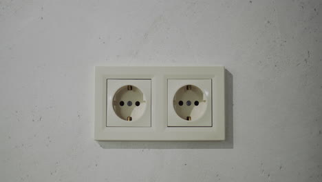 doble toma eléctrica de tipo europeo en la pared de la casa. la cámara se mueve lentamente hacia la pared con una toma de energía