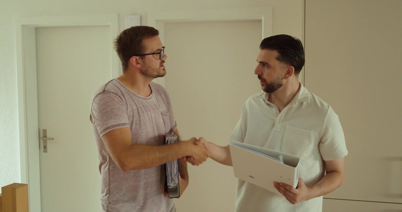 Due colleghi si stringono la mano dopo aver raggiunto un accordo di successo mentre tengono in mano documenti aziendali. Concetto di partnership, fiducia, lavoro di squadra e collaborazione aziendale di successo.