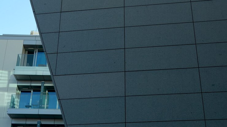 Architectural detail of a modern building corner with glass balustrades and a granite facade