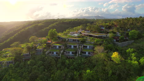 luxury hotel and resort in nusa penida bali surrounded by tropical nature and pool villas with private terraces, aerial rising with sunrise anamorphic light streak