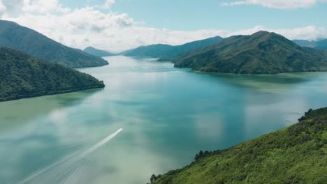 Stunning-aerial-view-of-small-boat-traveling-on-calm,-placid-waters-from-Havelock-through-idyllic-peninsula-landscape-of-Marlborough-Sounds-in-South-Island-of-New-Zealand-Aotearoa