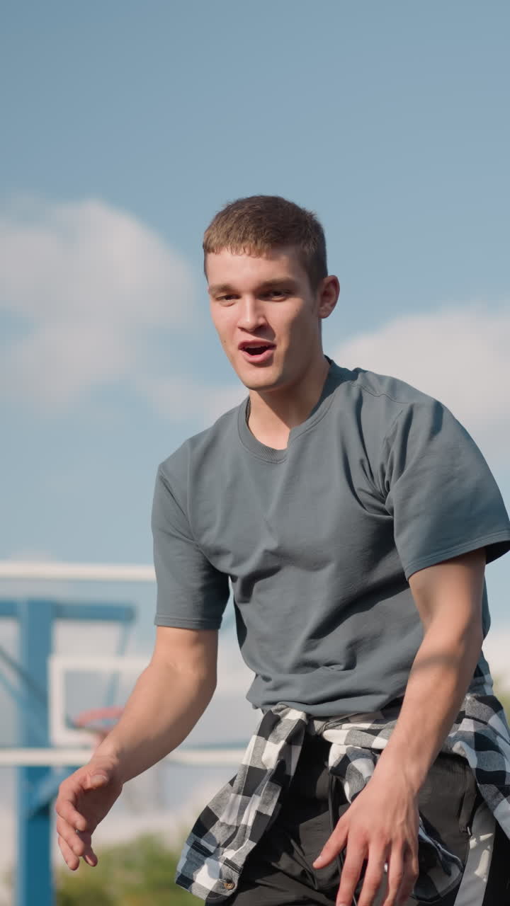 joven con tela a cuadros alrededor de la cintura salta para golpear la pelota de voleibol pero falla, sonriendo en respuesta, brillante cancha al aire libre con árboles y edificio en el fondo