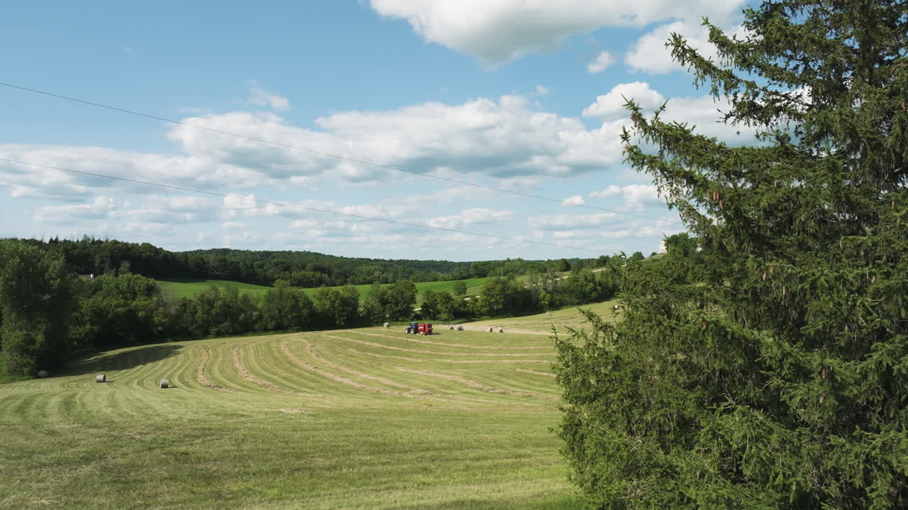 Plan aérien ascendant d'un tracteur sur un champ vert paisible et moissonné