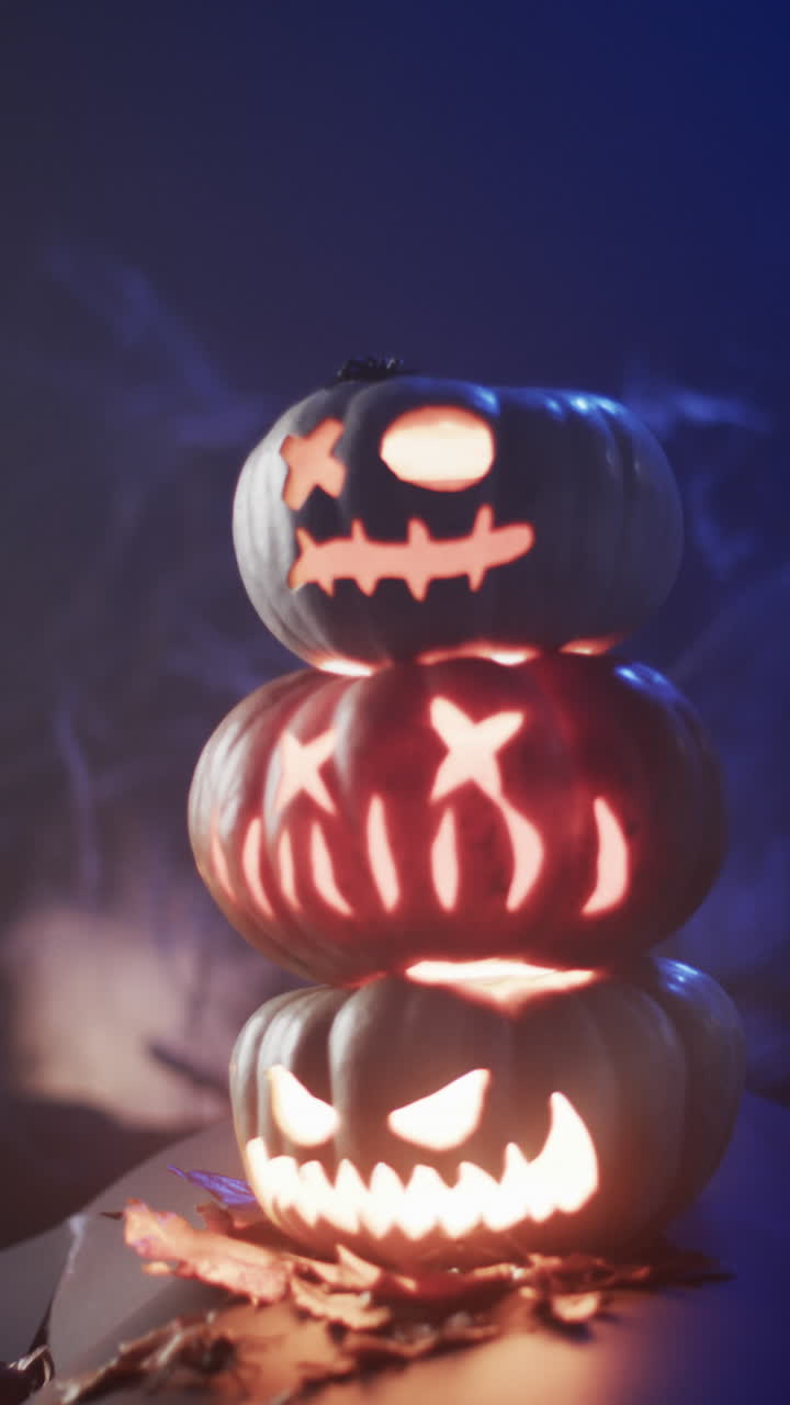 Vertical video of halloween carved pumpkins and smoke with copy space on blue background