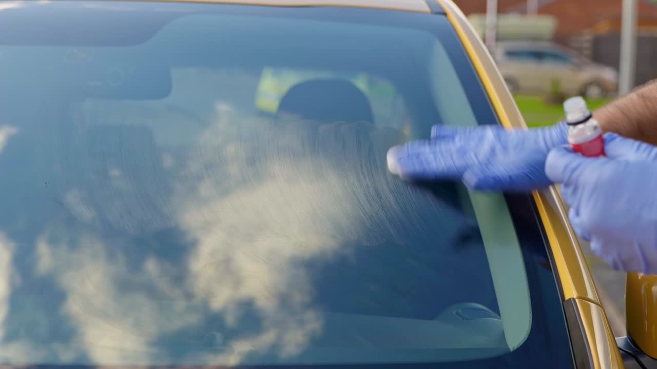 Applying ceramic coating to front window screen on a yellow car