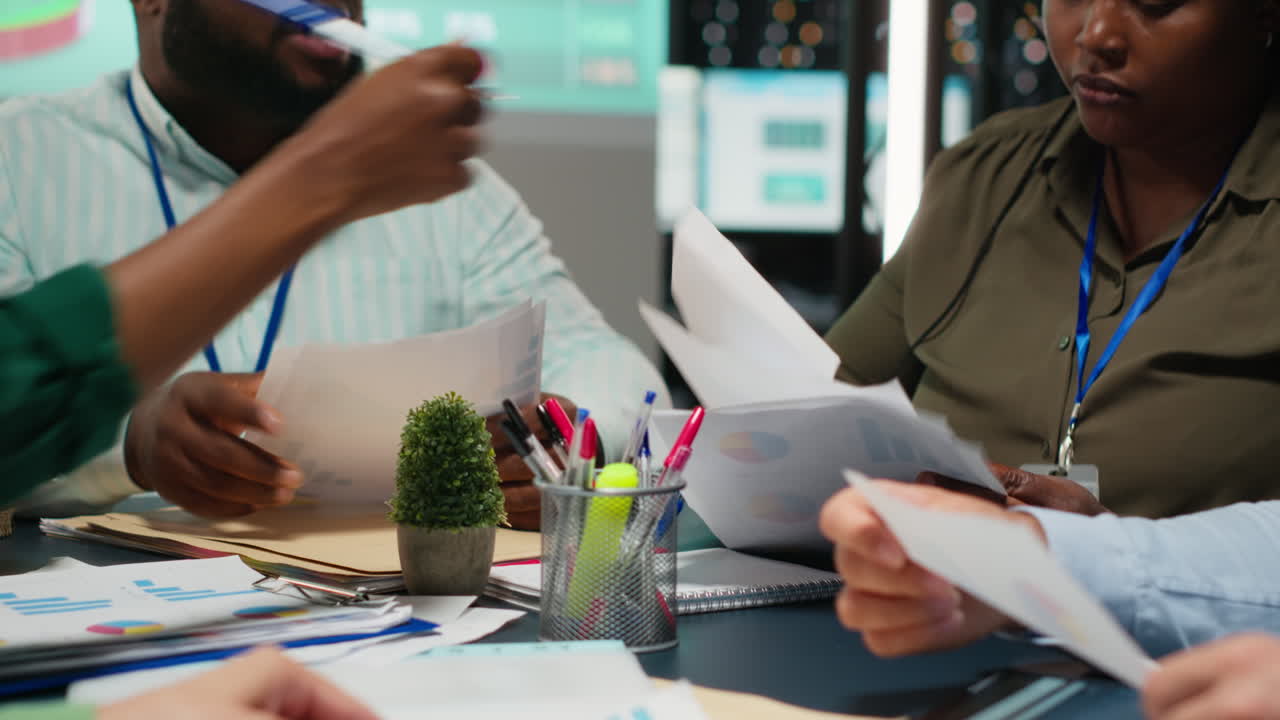 Multiethnic team reviewing infographics to offer solutions to fix project issues