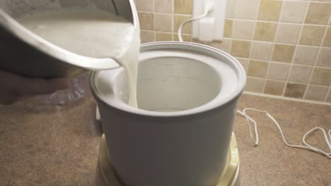 handheld shot of hands pouring vanilla ice cream mix into mixer